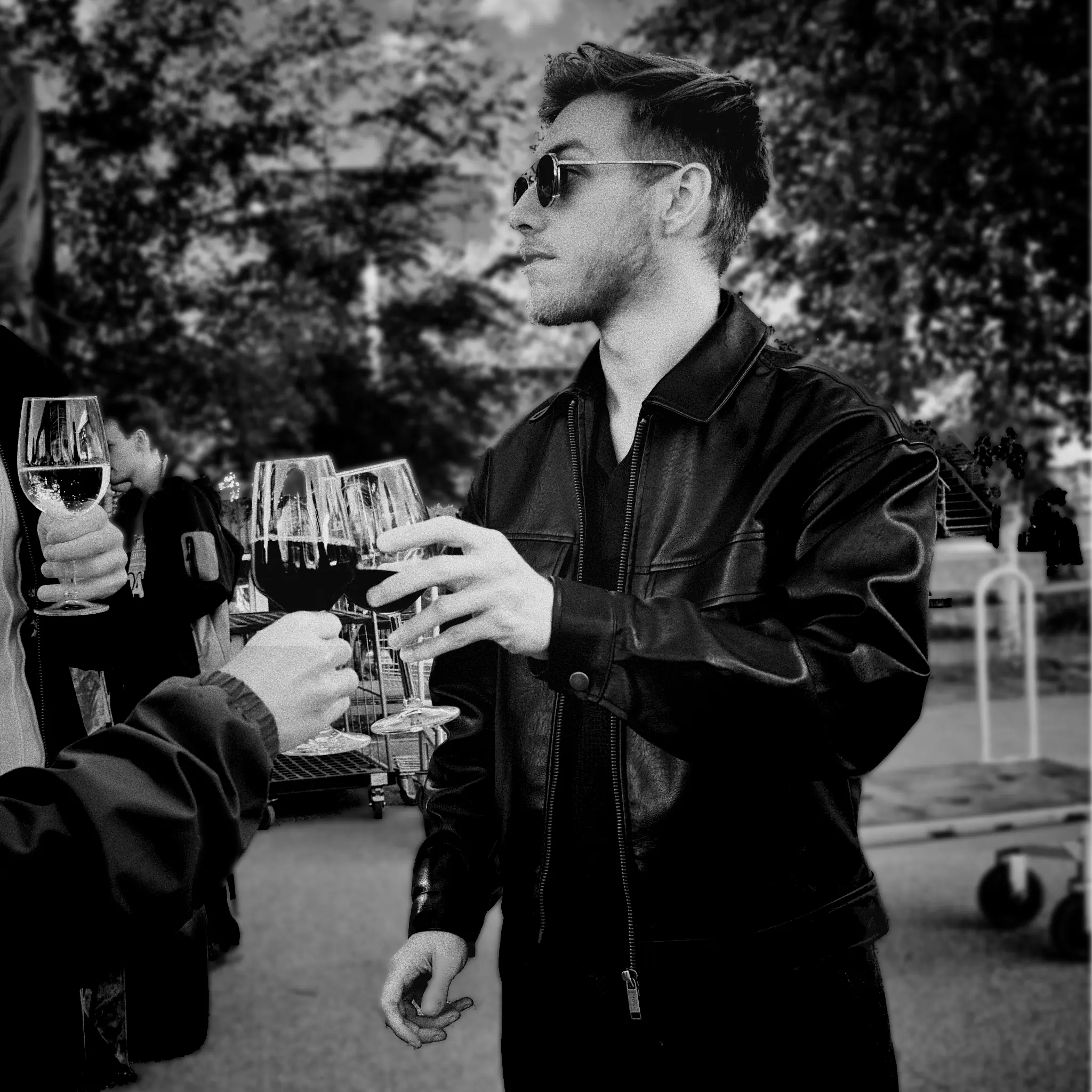 Male person holding a wine glass outdoors at an event.